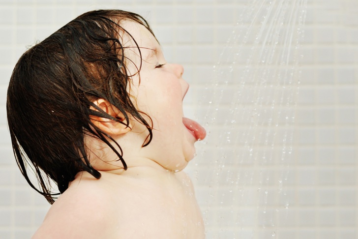 Little girl open months and enjoy shower water on tongue.